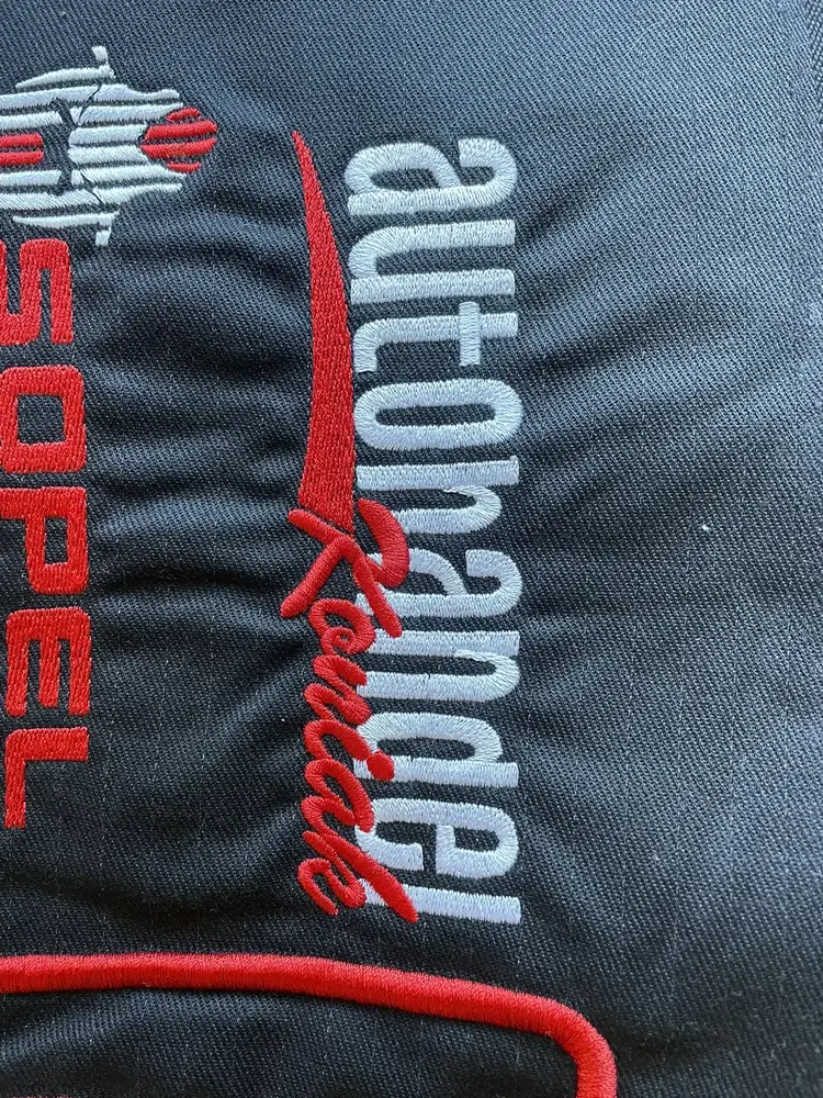 Haftowane logo firmy motoryzacyjnej na ciemnej odzieży roboczej