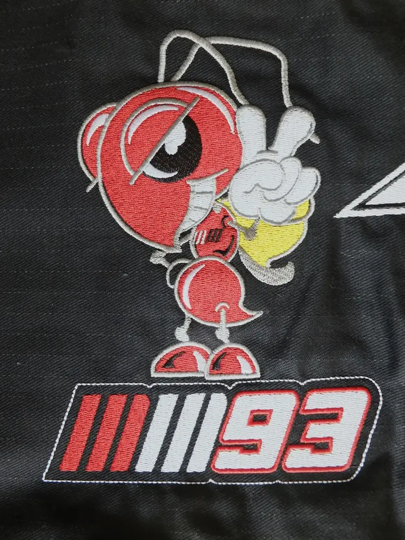 Haftowane logo motocyklowe z numerem startowym na ciemnej odzieży sportowej